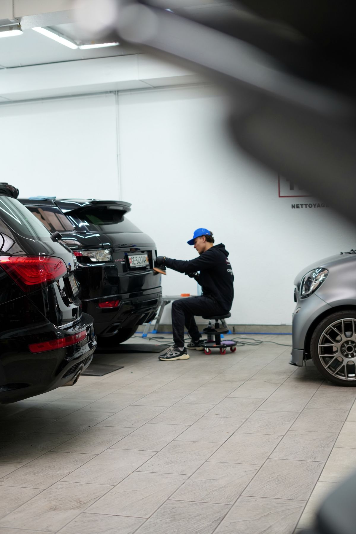 Polissage de la carrosserie d'un Range Rover noir à l'atelier